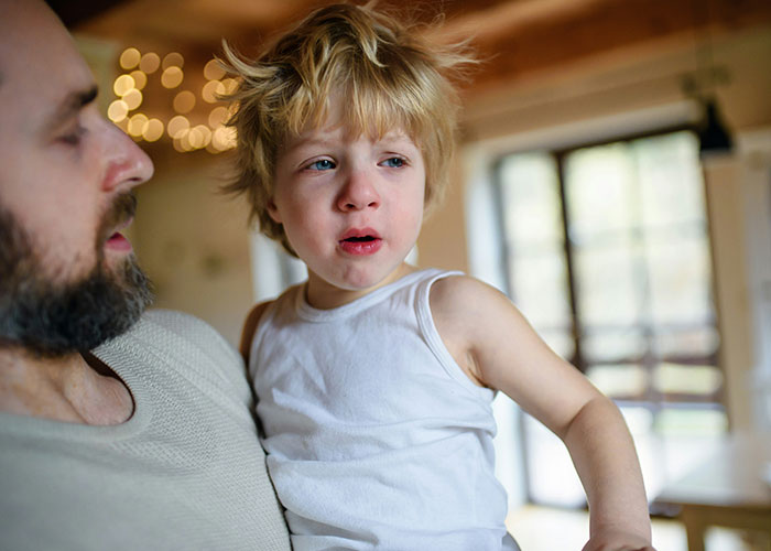 Man holding upset child indoors, concerned about how roommate’s guest treats her kid in a tense moment. Man holding upset child indoors, concerned about how roommate’s guest treats her kid in a tense moment.