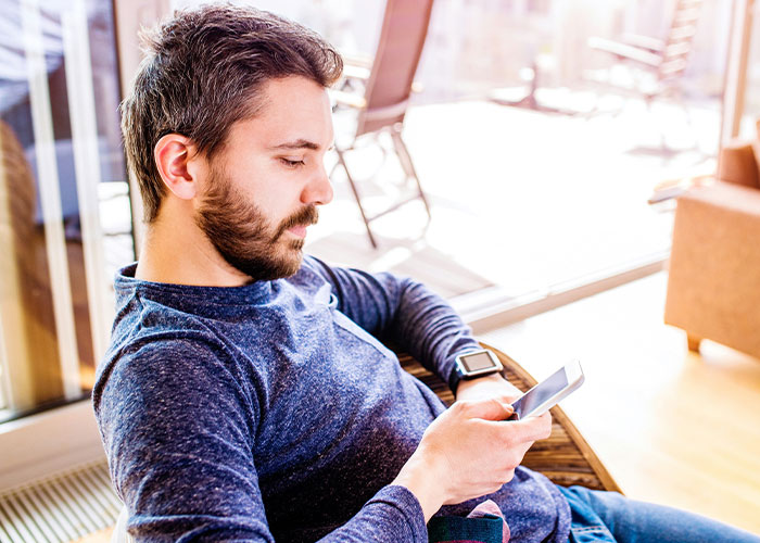 Man with kids looking concerned while using smartphone in bright room, reflecting worry about roommate’s guest and child treatment. Man with kids looking concerned while using smartphone in bright room, reflecting worry about roommate’s guest and child treatment.