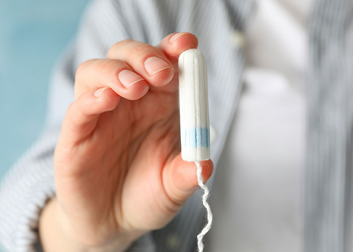 Hand holding a tampon, illustrating one of the things people can't believe they had to explain to another adult.