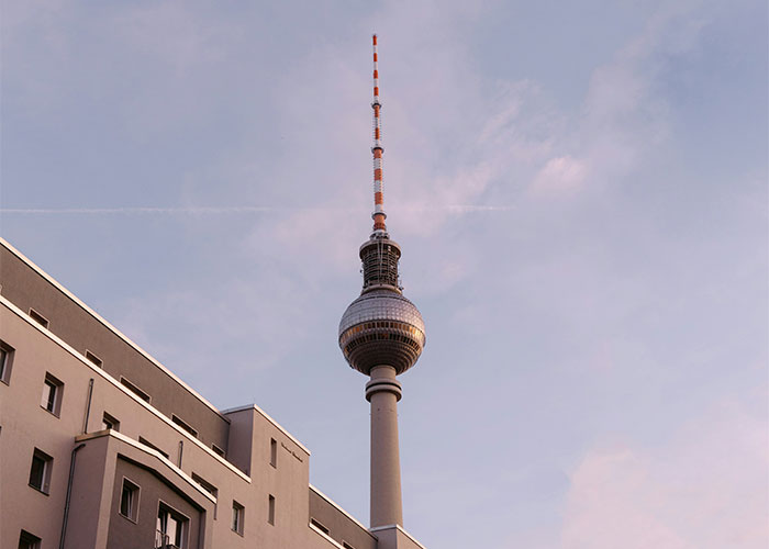 Berlin TV tower against a pastel sky with modern building in foreground representing things people can't believe explained