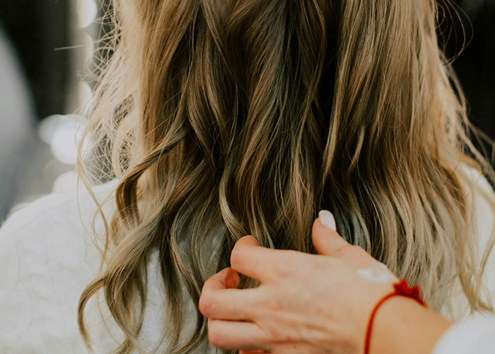 Person's hand touching long blonde hair, illustrating one of the things people can't believe they had to explain to another adult.