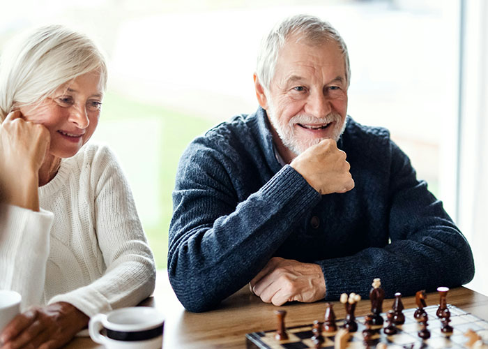 Two adults smiling while playing chess, illustrating surprising things people can't believe they had to explain.