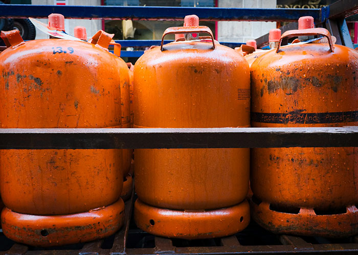 Three orange gas cylinders lined up on a metal rack, illustrating things people can't believe they had to explain.