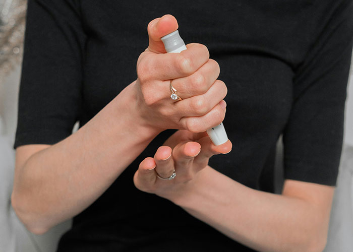 Person checking blood sugar with a lancet device, illustrating things people can't believe they had to explain to another adult.