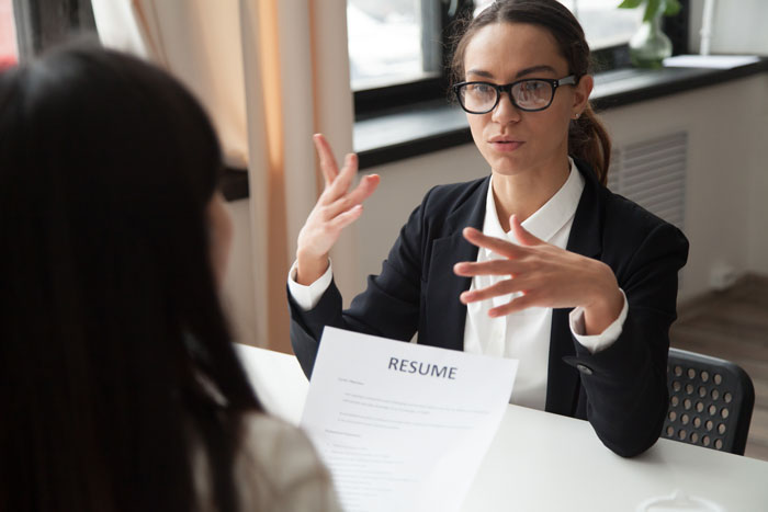 Career coach in black blazer giving detailed interview tips to help a candidate land dream jobs during a resume review session.