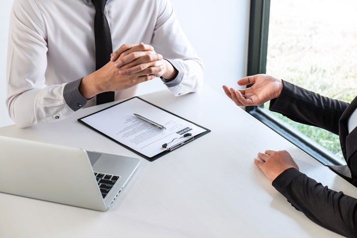 Professional career coach and client discussing interview tips with resume on desk in bright office setting.
