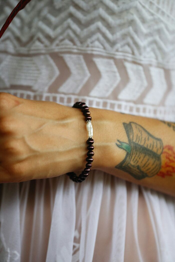 Close-up of a wrist with a beaded bracelet and tattoo, illustrating a personal style that cashiers judge customers for buying.