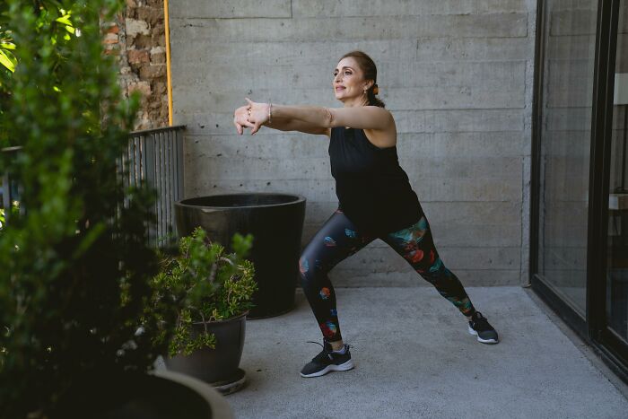Woman in sportswear stretching outdoors near plants, illustrating things cashiers judge customers for buying.