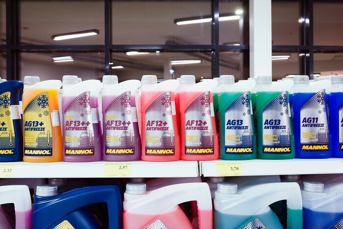 Various colorful antifreeze containers displayed on store shelves, a common product cashiers judge customers for buying.