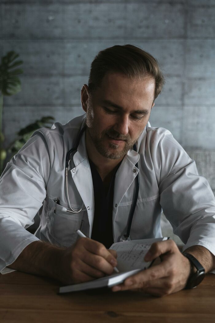 Man in a white coat writing notes with a stethoscope, visualizing cashier judgments on customer purchases.