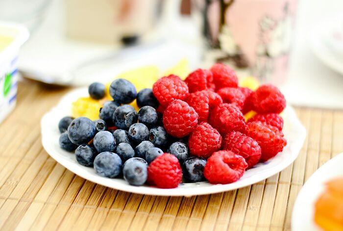 Plate of fresh blueberries and raspberries highlighting common foods that go bad more quickly than expected.