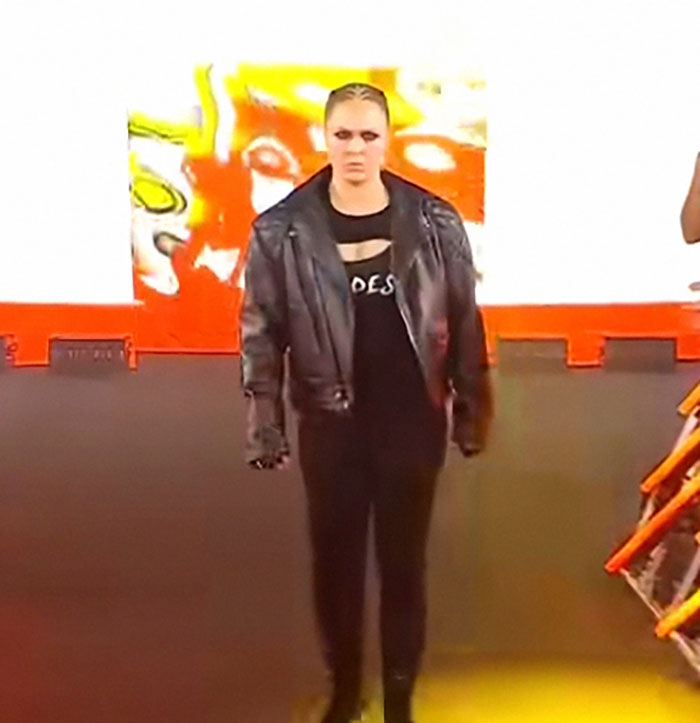 Person in a black leather jacket and dark outfit standing in front of a colorful background, showcasing celebrities before fame.