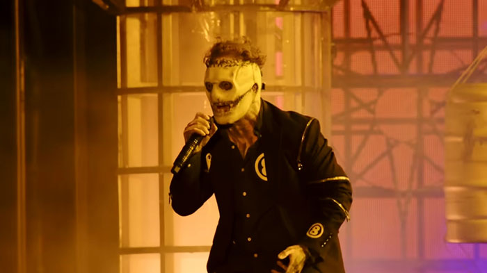 Performer wearing a skull mask and dark suit singing on stage, showcasing celebrities before their fame struck.