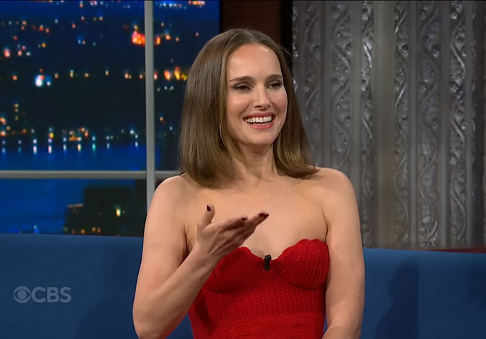 Actress in a red dress smiling and gesturing during a TV interview about celebrities before their fame.