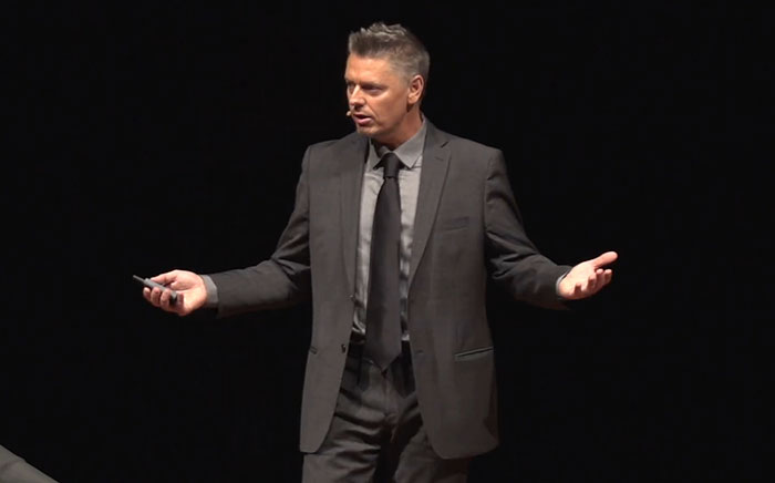 Man in a dark suit speaking on stage with open arms, illustrating netizens sharing stories about celebrities before their fame.