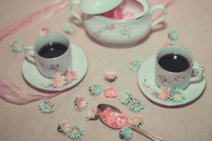 Two porcelain coffee cups with floral patterns on saucers surrounded by pastel flowers, illustrating funny girlfriend secrets.