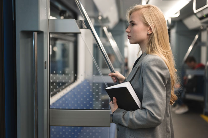 Young professional woman holding a notebook, standing in a subway, illustrating boss obsessed with punctuality and clever worker.