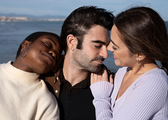Three people showing affection near the water, illustrating themes of relationships and cheating confessions.