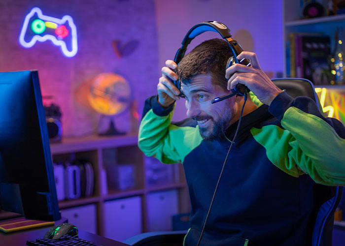 Man wearing a headset gaming in a colorful room, representing people sharing confessions about cheating on partners.