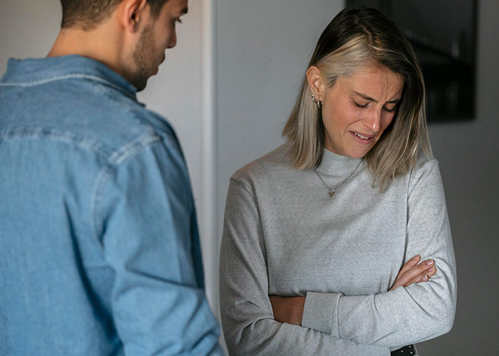 Woman looking upset and crying while a man in a denim shirt talks to her, illustrating themes of cheating confessions.