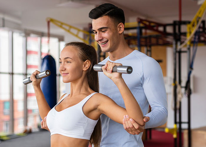 Couple working out together in a gym, focusing on partner support and strength training exercises.