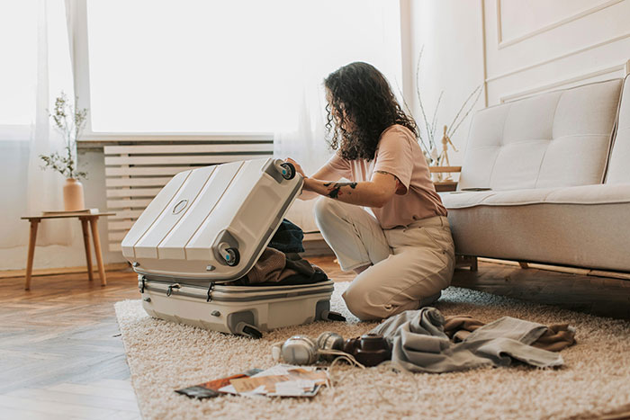 Woman quietly packing suitcase in living room, planning her exit after learning truth about boyfriend’s affair. Woman quietly packing suitcase in living room, planning her exit after learning truth about boyfriend’s affair.