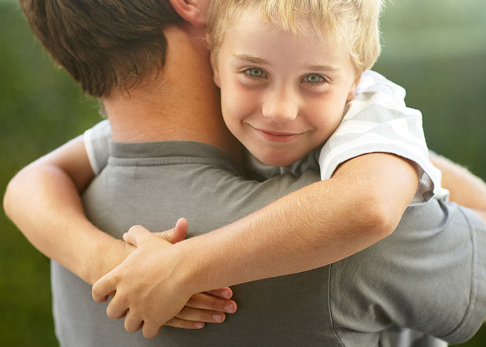 Child happily hugging an adult from behind, capturing young and dumb innocence without signs of cheating or paranoia.