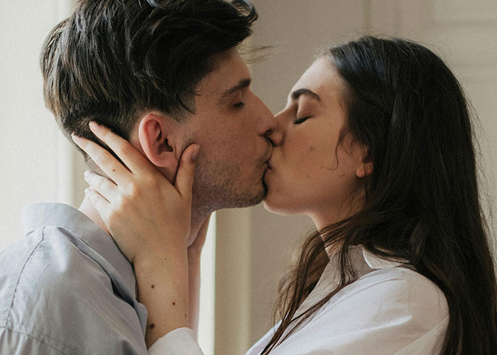 Couple sharing a close kiss indoors, illustrating signs of cheating suspicion and relationship trust issues.