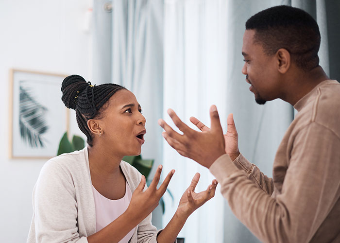 Young couple arguing indoors, showing signs of distrust and possible cheating concerns in their relationship.