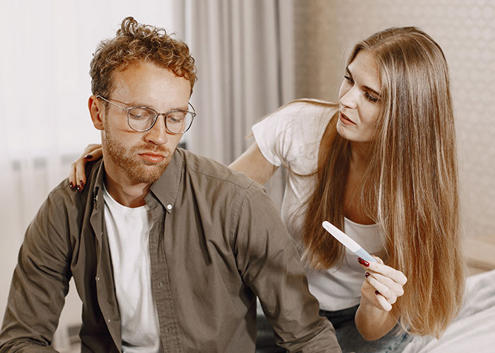 A concerned woman showing a pregnancy test to a man, illustrating signs that someone is cheating and relationship doubts.