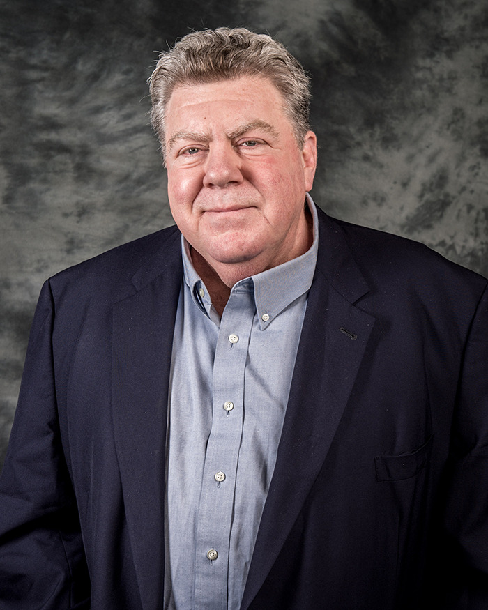 Middle-aged man in a dark blazer and blue shirt posing against a gray backdrop, Cheers star fans heartbroken after passing news