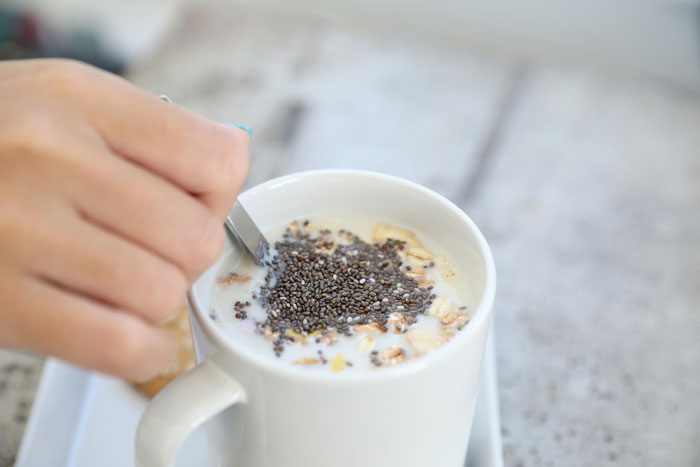 Hand stirring milk and oats topped with chia seeds in a white mug, highlighting chia seeds change diet benefits. Hand stirring milk and oats topped with chia seeds in a white mug, highlighting chia seeds change diet benefits.