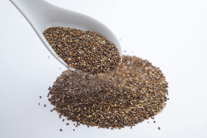 Close-up of chia seeds being poured from a white scoop onto a pile, highlighting chia seeds in diet change. Close-up of chia seeds being poured from a white scoop onto a pile, highlighting chia seeds in diet change.