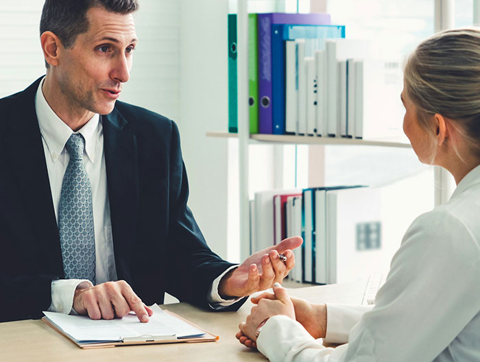 Man in a suit discussing an extra risky work nomination with a female colleague in a modern office setting.