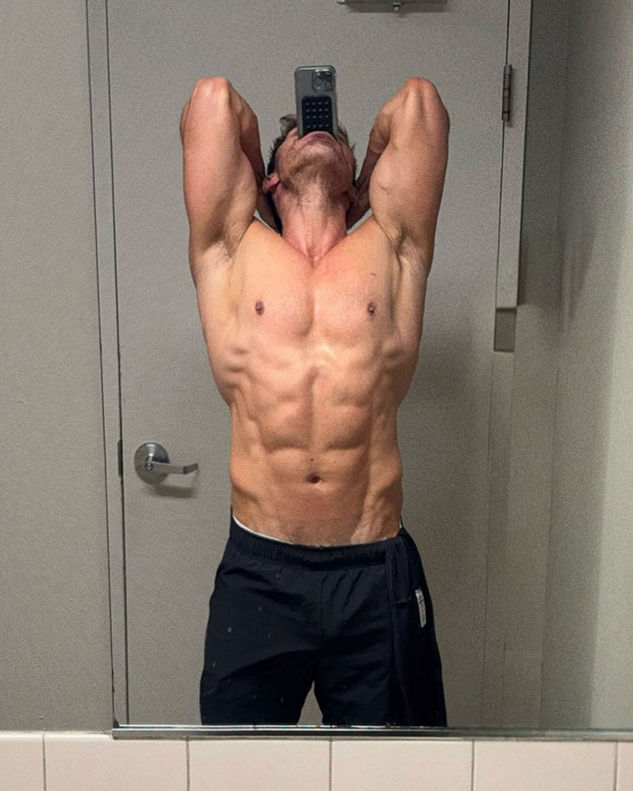 Male hair stylist showing muscular body and bulge in a speedo while taking a mirror selfie in a minimal bathroom setting. Male hair stylist showing muscular body and bulge in a speedo while taking a mirror selfie in a minimal bathroom setting.