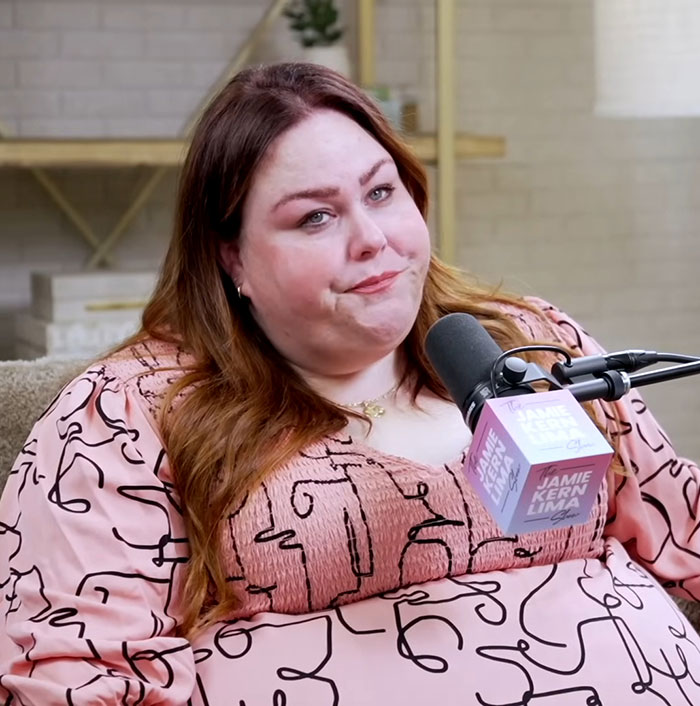 Chrissy Metz speaking into a microphone during a podcast, showing her weight loss and slimmed-down look.