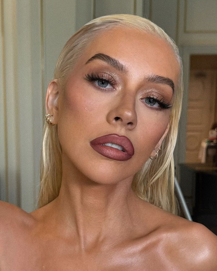 Close-up of Christina Aguilera with sleek blonde hair and bold makeup fueling Ozempic and surgery rumors. Close-up of Christina Aguilera with sleek blonde hair and bold makeup fueling Ozempic and surgery rumors.