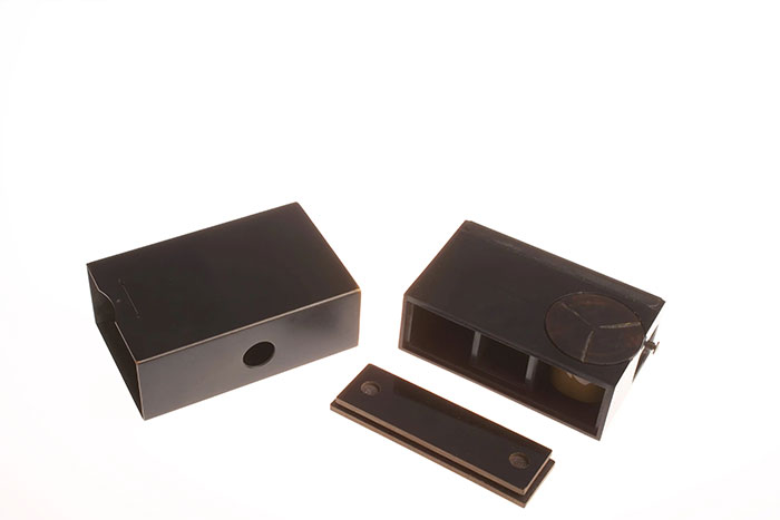 Black vintage CIA spy technology device parts arranged on a white background showing ingenuity in covert equipment design.