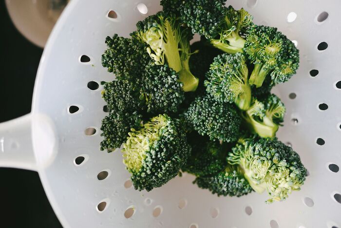 Broccoli florets in a white colander representing food prices side-by-side comparisons in the 1980s and now
