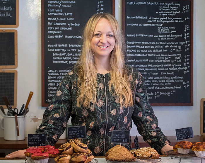 Woman standing behind a counter with baked goods, representing Meghan Markle allegedly berating her wedding caterer.