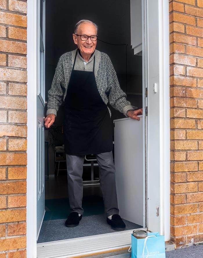 Elderly man wearing an apron standing in a doorway, symbolizing dark family secrets revealed in adulthood.