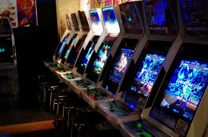 Row of retro arcade game machines with colorful screens lighting up a dark room, highlighting Gen X nostalgia and gaming culture.