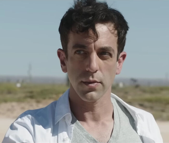 Man in a white shirt outdoors, looking away thoughtfully, capturing the essence of celebrity gossip discussions.