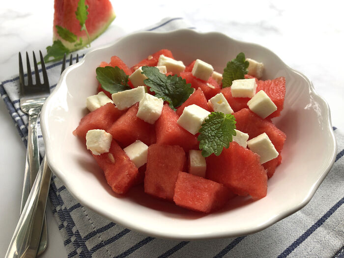 Bowl of fresh watermelon salad with feta cheese cubes and green herbs, illustrating wild cooking opinions.