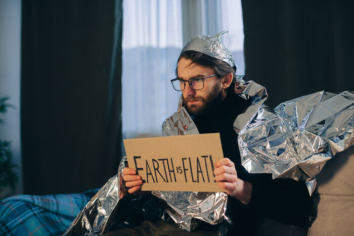 Man wrapped in foil hat and blanket holding a sign, illustrating people who called off their wedding reasons.