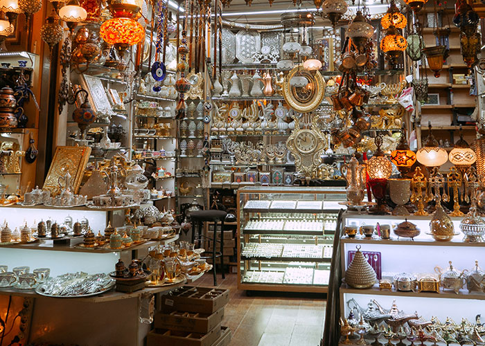 Traditional Middle Eastern market filled with lamps, silverware, and decorative items reflecting national stereotypes humorously.