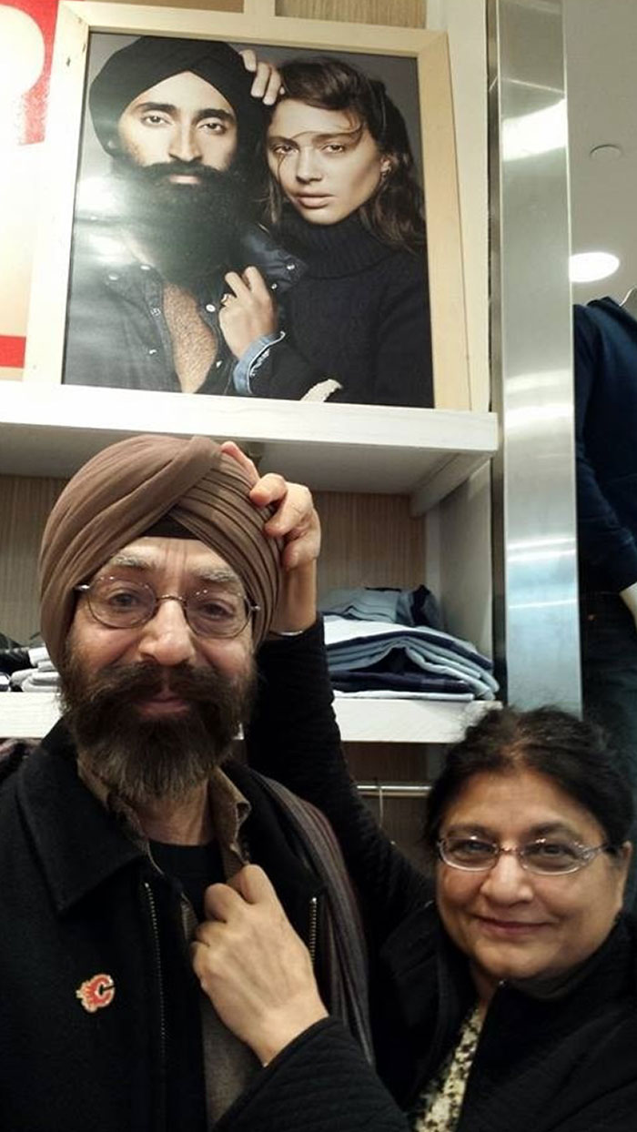 Older couple smiling together below a framed photo, showing time changed people but not their love for each other.