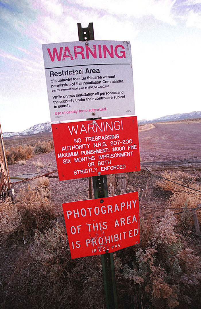 Warning signs for restricted area and no photography in a desert setting hint at craziest conspiracy theories on the internet.
