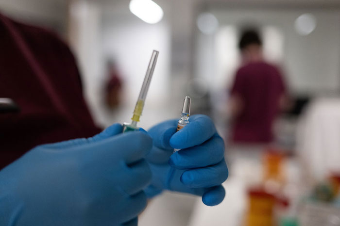Gloved hands holding a syringe and vial, representing craziest conspiracy theories about vaccines on the internet.