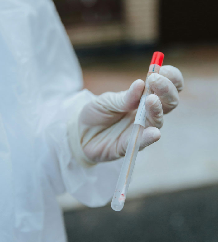 Close-up of a gloved hand holding a test tube outdoors, illustrating craziest conspiracy theories about medical testing.